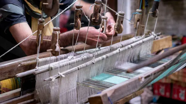 Kashan, Iran - May 2019: Iranian man crafting a wool carpet on the cotton strings in the carpet workshop