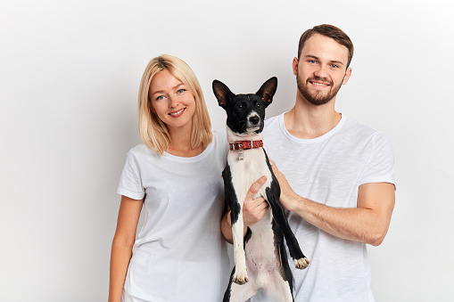 smiling cheerful young man and woman in white T-shirts holding their pet and looking at the camera.free time, pastime, leisure, animal lovers