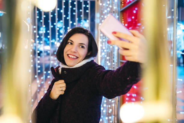 istock Woman making selfie among Christmas string lights 1181603124