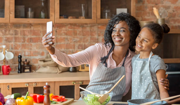 istock Cheerful mom and daughter taking selfie while cooking at kitchen 1181603301