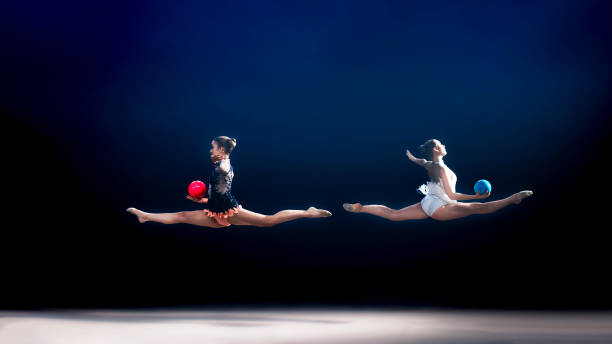 gymnasts performing with balls - the splits ethnic women exercising imagens e fotografias de stock