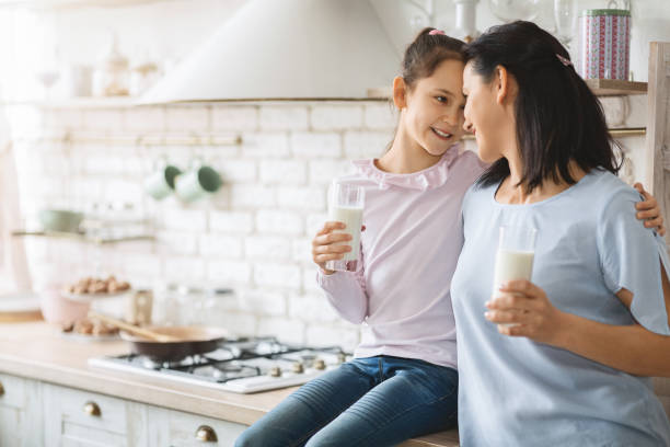 istock Young single mother and daughter drinking milk in kitchen together 1181604241