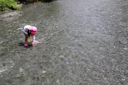 Japanese girl playing in the river with water gun (4 years old)