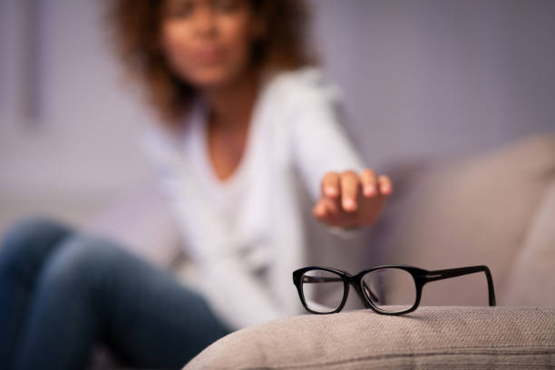 eyesight problem. woman reaching for eyeglasses on sofa - female emotional stress african ethnicity loss imagens e fotografias de stock