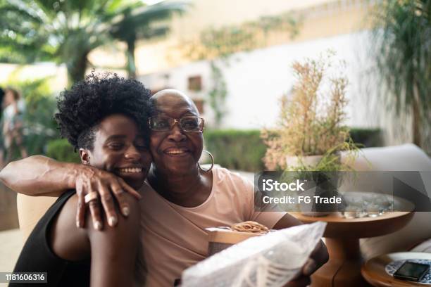 Granddaughter Giving A Surprise Gift To Grandmother Stock Photo - Download Image Now