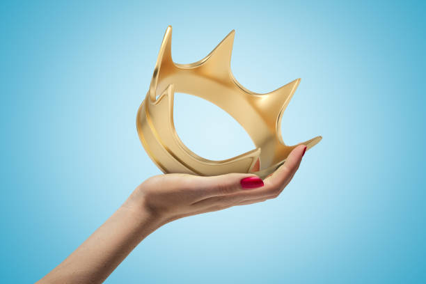 istock Female hand holding golden crown on blue background 1181607143