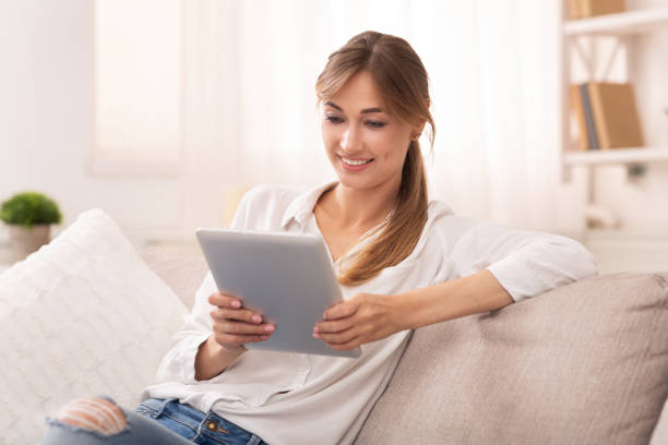 istock Smiling Woman Using Digital Tablet Relaxing On Sofa At Home 1181607322