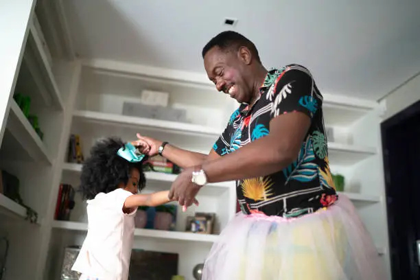 Funny grandfather with tutu skirts dancing like ballerinas with grand daughter