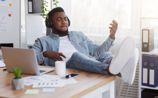 istock Cheerful employee playing virtual guitar while listening music at workplace 1181607697