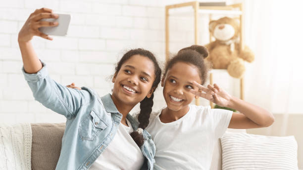 istock Black cheerful sisters taking selfie at home 1181607947