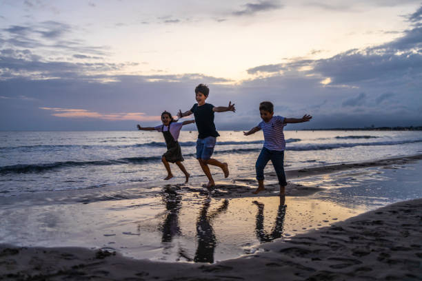 istock Three kids running on the beach at sunset 1181608001