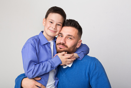 Happy family portrait. Cute boy embracing his father, white studio background