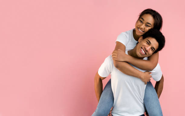 istock Loving guy piggybacking his girlfriend on pink background 1181609375
