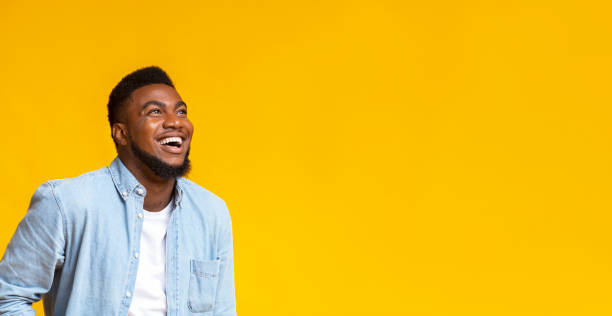Black man looking at copy space with ecstatic face expression Awesome sales. Ecstatic african american guy looking up at copy space with amazement, isolated on yellow background men hairstyle afro cool stock pictures, royalty-free photos & images