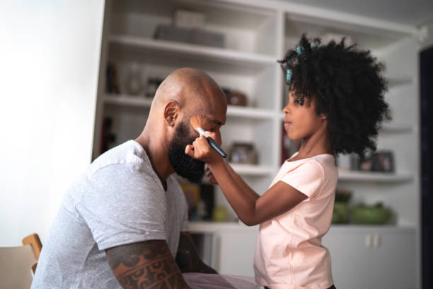 Daughter doing makeup to shy father at home