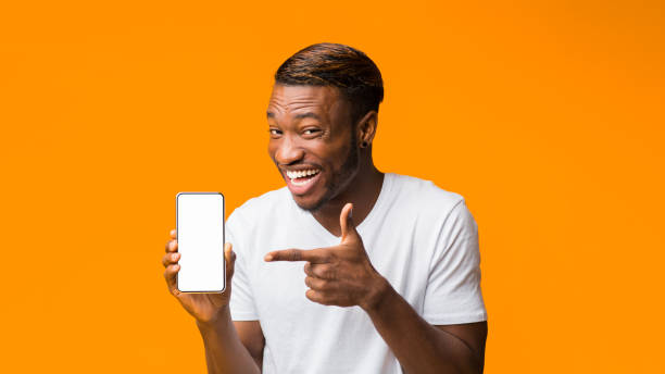 istock Black Man Showing Phone Blank Screen Standing, Orange Background, Mockup 1181612287