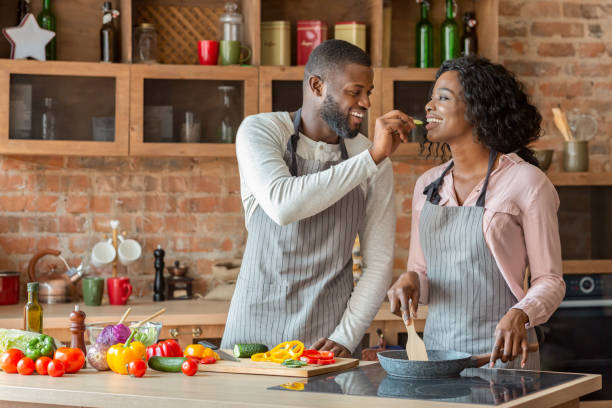 istock Man feeding his woman while cooking together at kitchen 1181612557