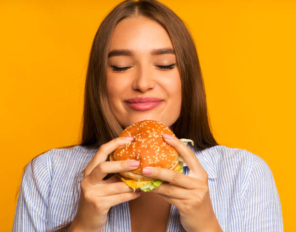 istock Happy Girl Eating Burger Standing, Studio Shot 1181612624