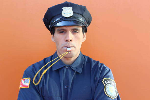 istock Policeman blowing whistle in orange background 1181612783