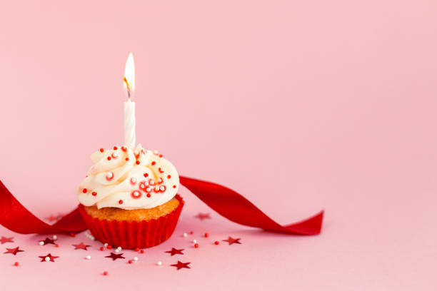 cupcake di compleanno con glassa al burro, nastro rosso e candela su sfondo pastello rosa. - 2232 foto e immagini stock