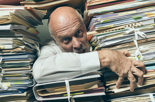 Panicked stressed businessman overloaded with paperwork, he is asking for help and assistance