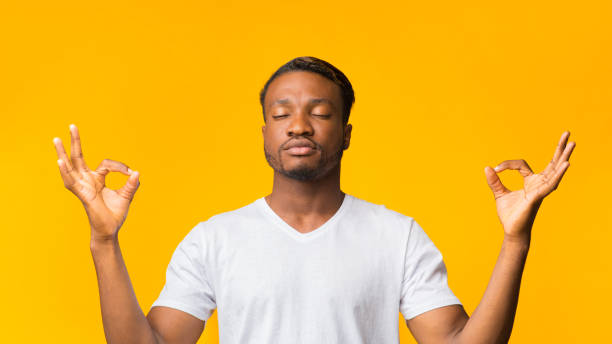 istock Black Man Meditating Standing Over Yellow Background, Panorama 1181613306