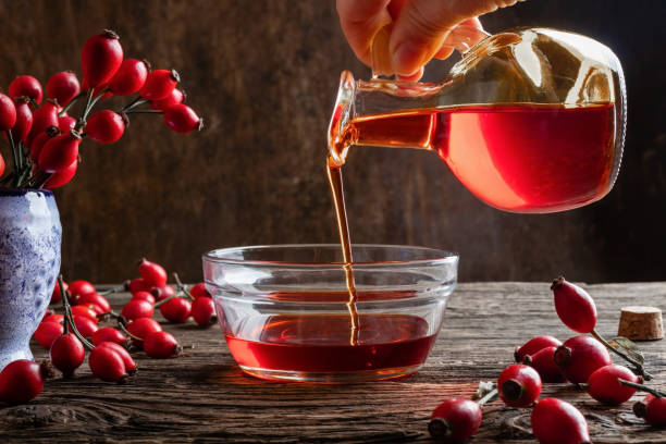 gießen rose hüftkernöl in eine schüssel - red jug stock-fotos und bilder