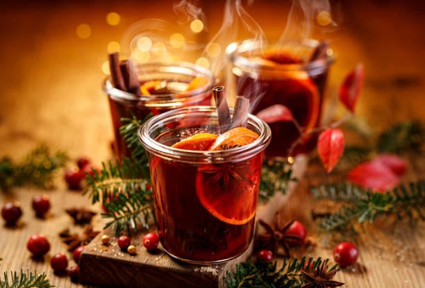 Christmas mulled red wine with aromatic spices and citrus fruits on a wooden rustic table, close-up.