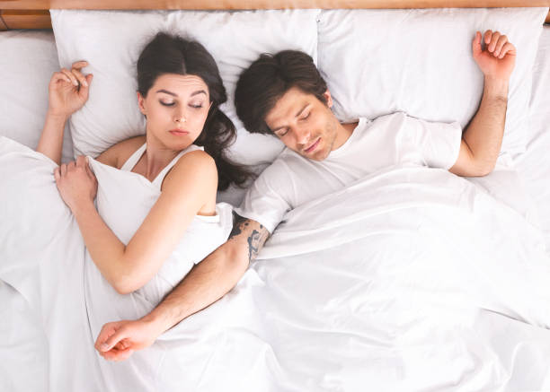 istock Young woman suffering from her sprawled man in bed 1181619514