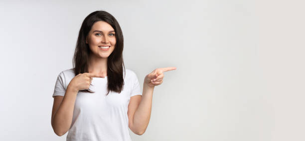 istock Cheerful Lady Pointing Fingers Aside Standing In Studio, Panorama 1181619629