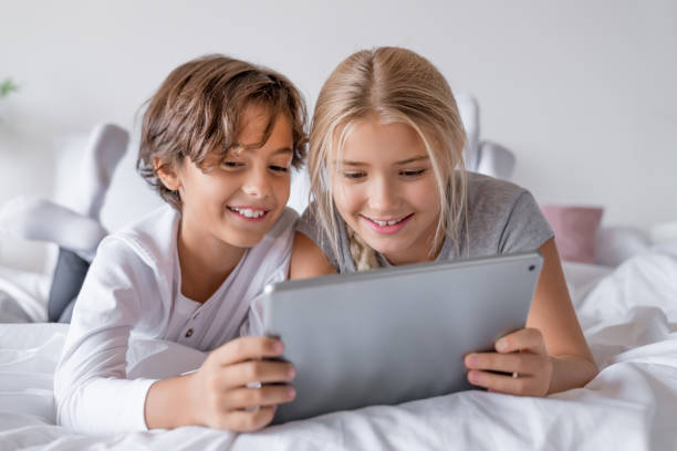 istock Cute little children with digital tablet using internet at home 1181620572