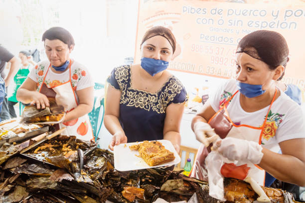 mujer mostrando pibes, plato tradicional de maíz de pollo envuelto en hojas de plátano vendidos por el día de los muertos en san sebastián park en mérida, yucatán, méxico - leafes fotografías e imágenes de stock