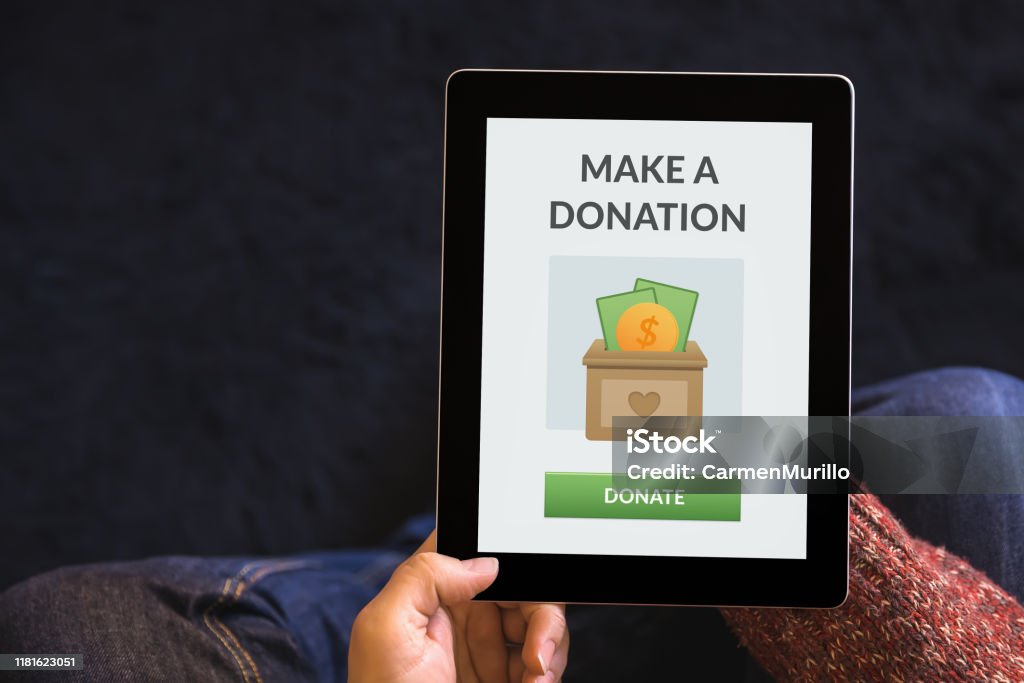 Hands holding tablet with donation concept on screen Hands holding digital tablet computer with donation concept on screen. Top view Charitable Donation Stock Photo