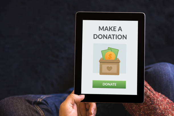 Hands holding tablet with donation concept on screen stock photo