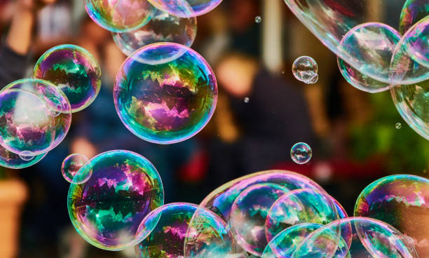 bulle colorée lumineuse métallique de savon dans l'air devant un fond abstrait flou - bubble foil photos et images de collection
