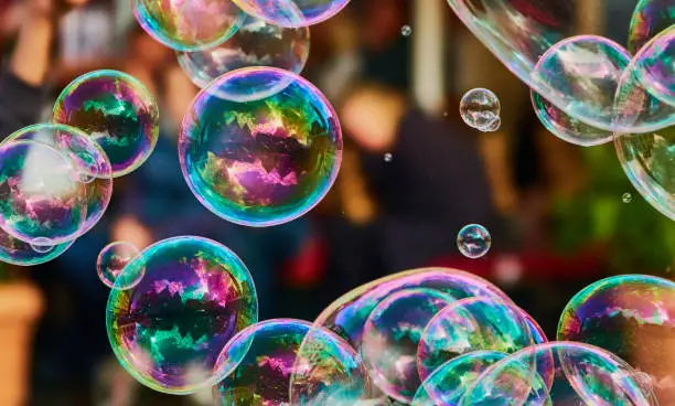 Metallic glowing colorful soap bubbles in the air in front of a blurry abstract background