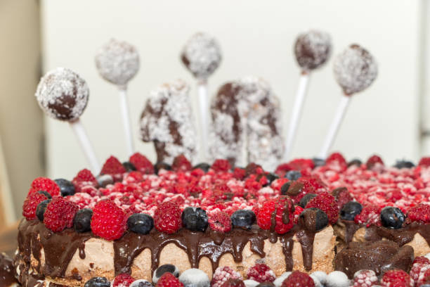A festive cake made from natural ingredients, decorated with raspberries, blueberries and chocolate balls spoiled with coconut. On the cake is the number ten. Background for anniversary or birthday
