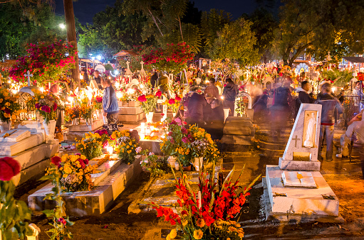 Oaxaca - Mexico, 11/01/2014: Movement in the Oaxaca Cemetery in Mexico. In the early hours of November 1st to November 2nd, the local community gathers in the cemetery to celebrate Day of the Dead, when, according to Mexican belief, the souls of the dead return to visit their families. During the celebration the tombs are adorned with flowers, candles and the favorite foods of the deceased as a way to welcome their souls in a joyful way.