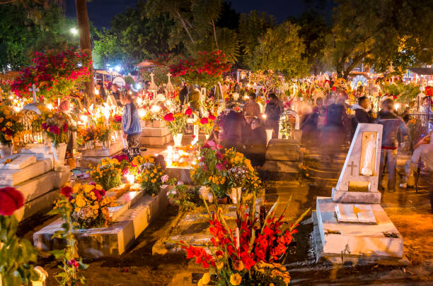 Celebration of the Day of the Dead in Oaxaca, Mexico Oaxaca - Mexico, 11/01/2014: Movement in the Oaxaca Cemetery in Mexico. In the early hours of November 1st to November 2nd, the local community gathers in the cemetery to celebrate Day of the Dead, when, according to Mexican belief, the souls of the dead return to visit their families. During the celebration the tombs are adorned with flowers, candles and the favorite foods of the deceased as a way to welcome their souls in a joyful way. day of the dead photos stock pictures, royalty-free photos & images