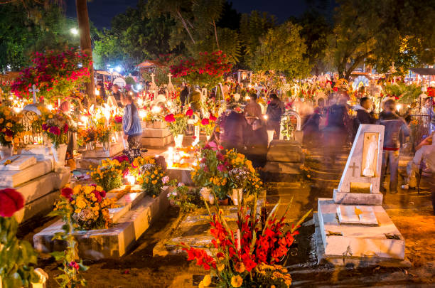 Celebration of the Day of the Dead in Oaxaca, Mexico Oaxaca - Mexico, 11/01/2014: Movement in the Oaxaca Cemetery in Mexico. In the early hours of November 1st to November 2nd, the local community gathers in the cemetery to celebrate Day of the Dead, when, according to Mexican belief, the souls of the dead return to visit their families. During the celebration the tombs are adorned with flowers, candles and the favorite foods of the deceased as a way to welcome their souls in a joyful way. mexican day of the dead stock pictures, royalty-free photos & images