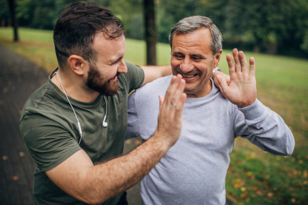 мужчина и сын, осуществляющие в парке вместе - outdoors adult child sport стоковые фото и изображения