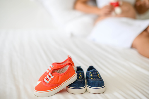 Small shoes pregnant woman. happy waiting small baby , relaxing at home in bedroom.