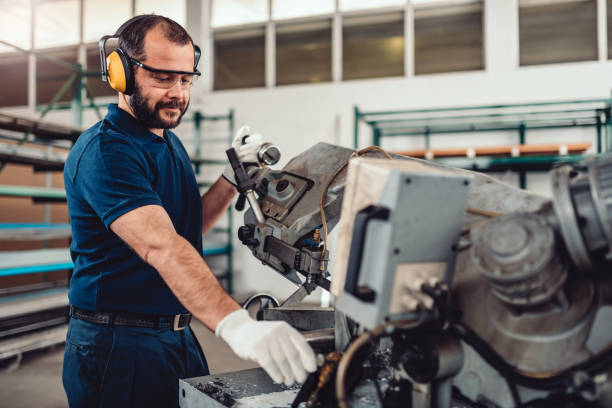 Factory worker operating band saw cutting machine