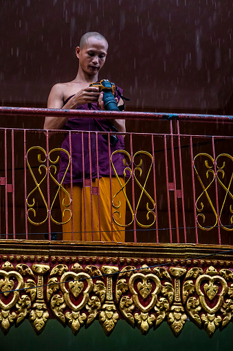 Phnom penh, Cambodia - August 28, 2019: Buddhist Young Monk Photographer, photographing under raining cats and dogs.