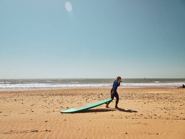 istock Surfer girl dragging the surf on a sand beach 1181633417