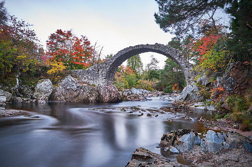 Old bridge in scotland where the river flows underneath the rocks in the fall.