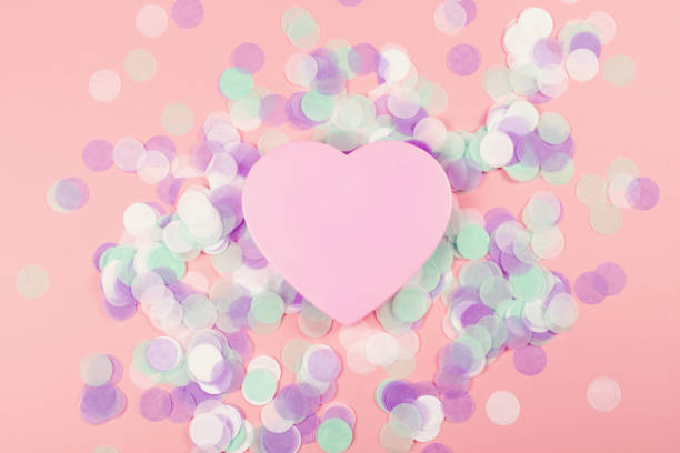 istock Plastic heart on pink background with confetti. 1181634899