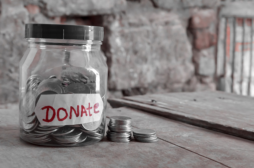 Donate written jar on wooden ,donate written red colors,and coins,coins donate jar