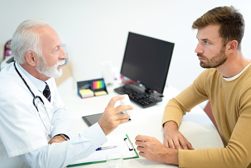 Senior male doctor prescribing a medicine to young male patient.