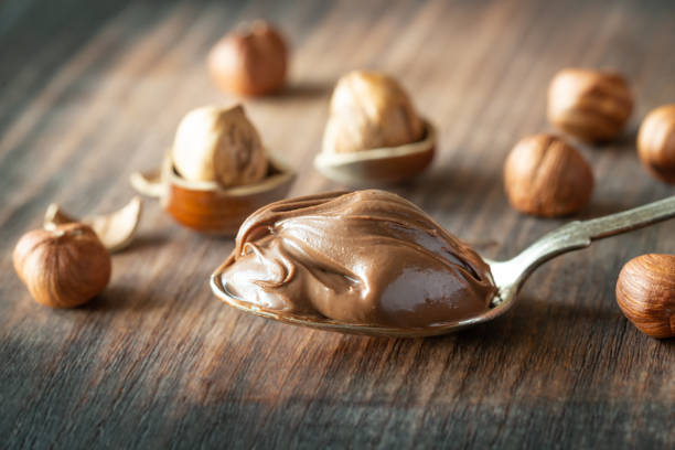 Spoon of chocolate paste with hazelnuts Spoon of chocolate paste with hazelnuts on the wooden background Teaspoon of Nutella stock pictures, royalty-free photos & images